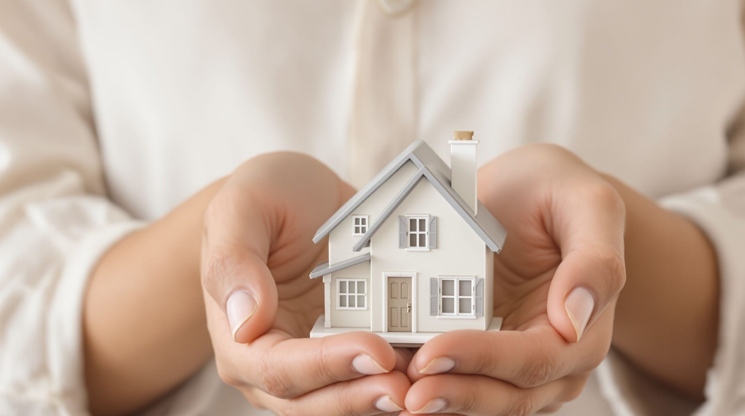 Person holding a tiny model house